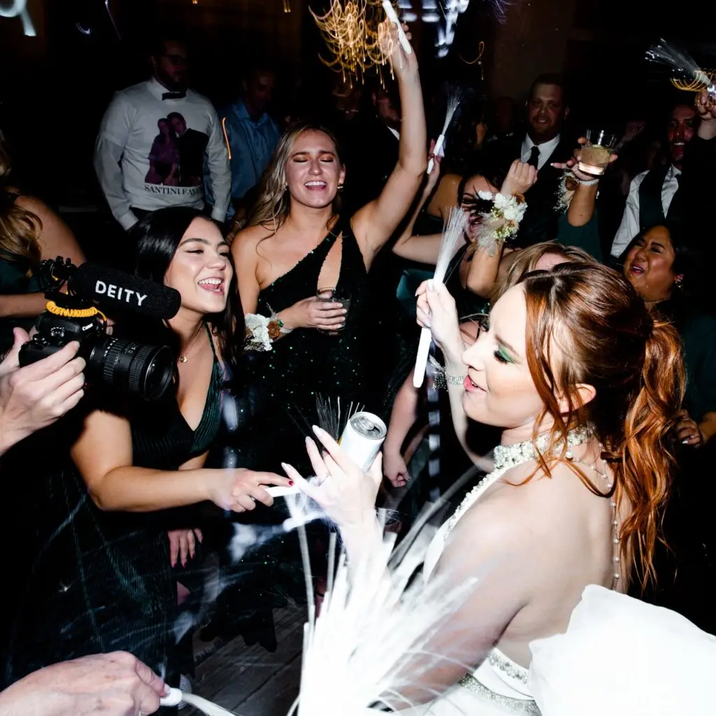 Bride and group of friends dancing with sparklers and drinks