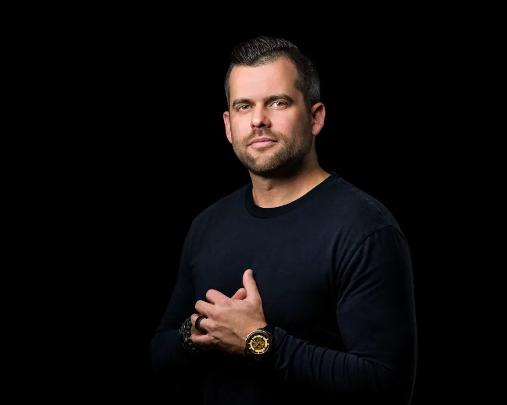 Justin Kada on a black background, wearing a black shirt